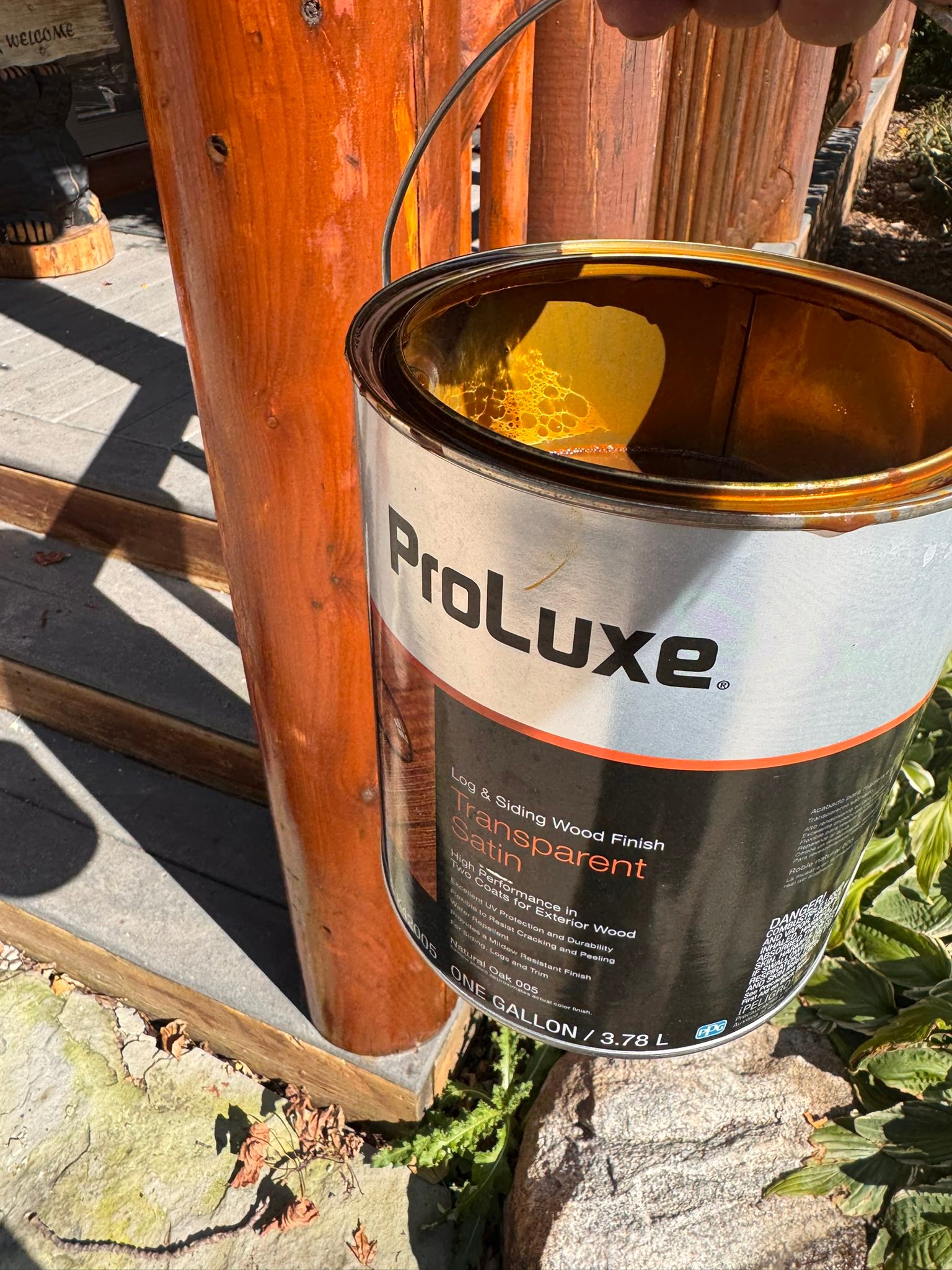 ProLuxe transparent satin wood stain being applied to a log home support post — process shot