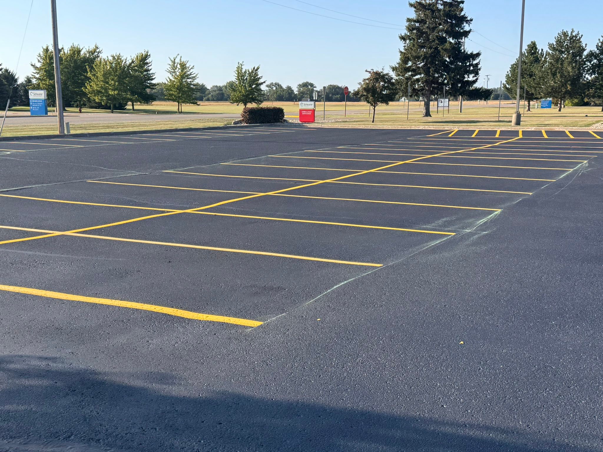 Large commercial parking lot restripe with fresh yellow lines at a Bad Axe hospital